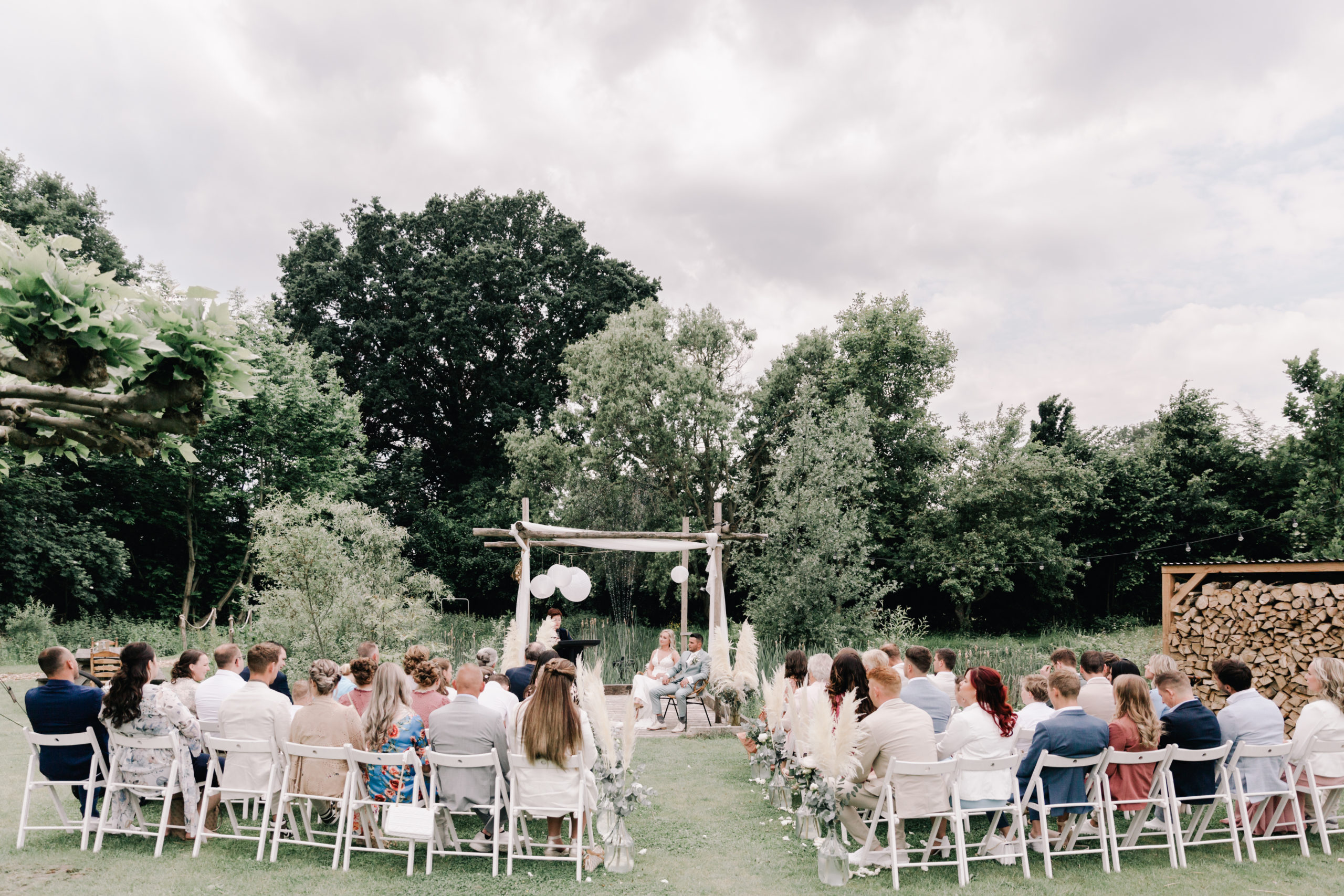 festivalbruiloft met buiten ceremonie witte houten stoelen pluimen fotografie door lianne